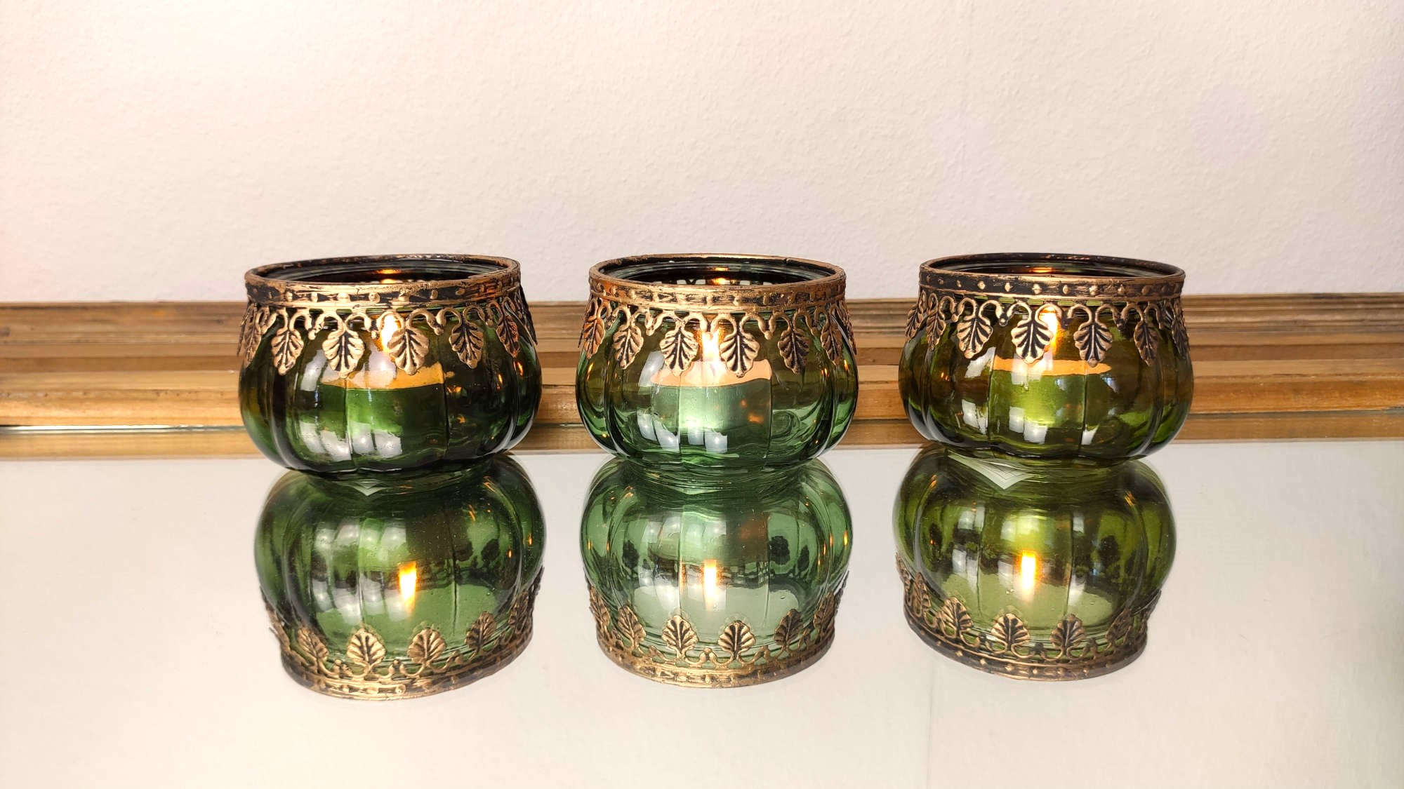 Produktbild Teelichthalter Drei gruene Teelichthalter Set mit Metall Rand auf einem Glastisch